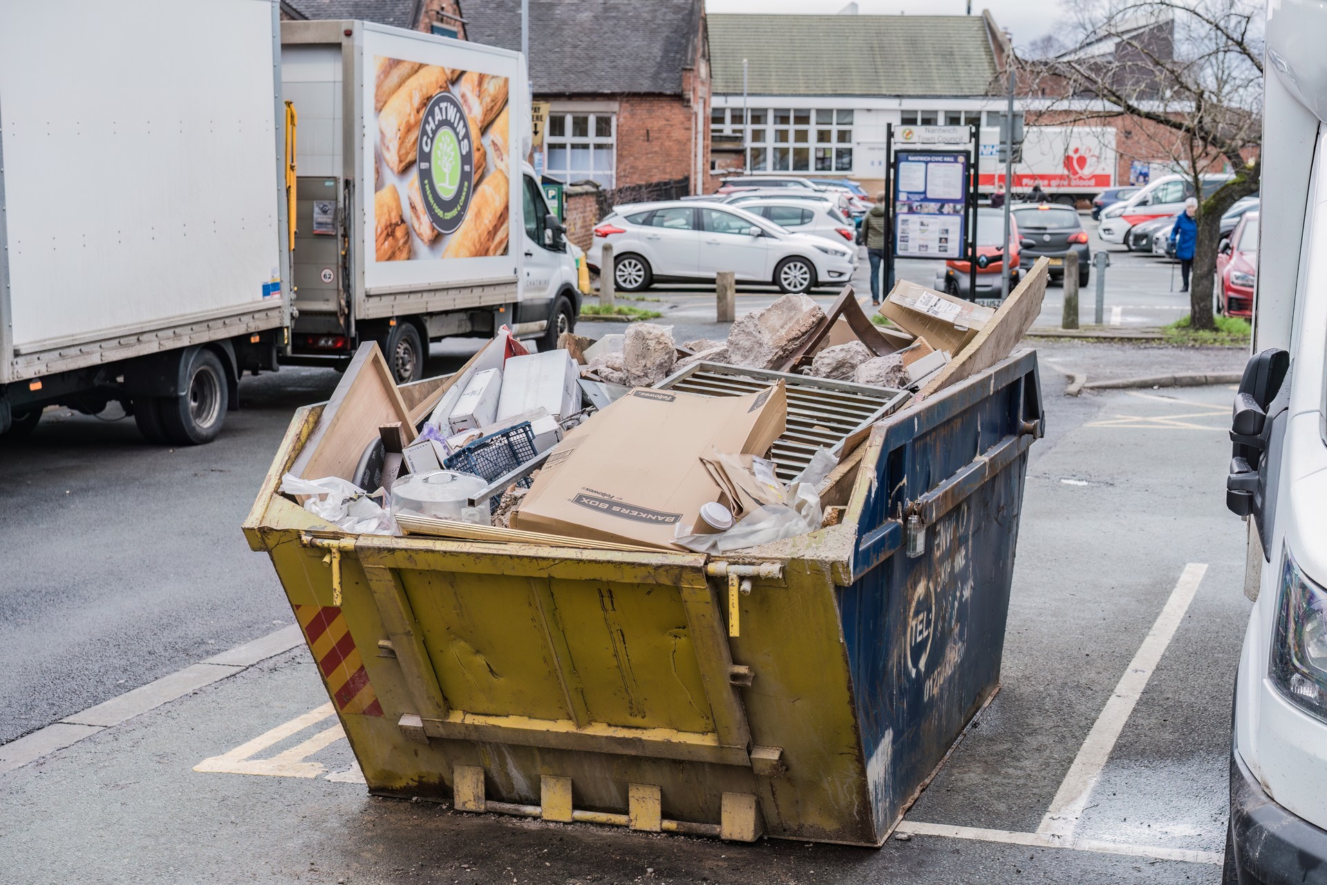 Industrial Yellow Rubbish Skip Outside Loaded With Trash And Disposable Waste